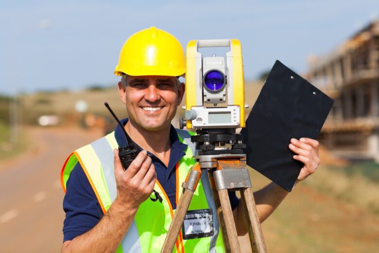 happy senior land surveyor with tacheometer on construction site